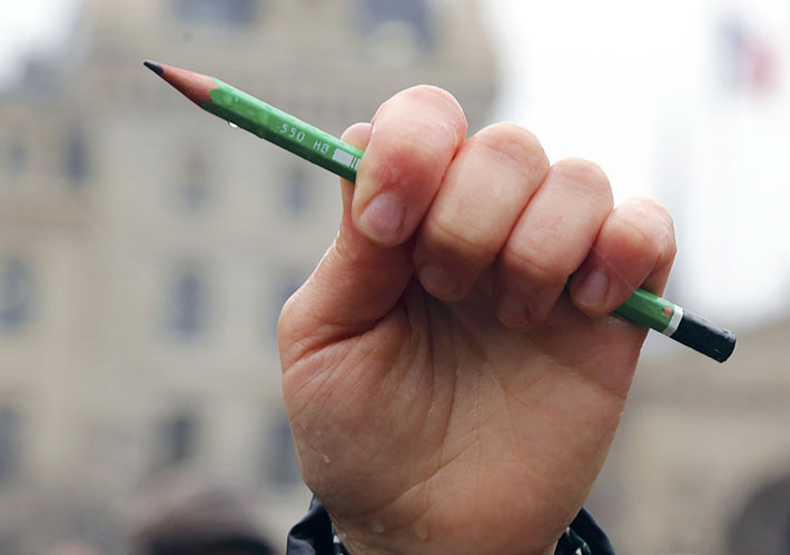A citizen holds a pen in front of the Notre Dame Cathedral in Paris during a minute of silence for victims of the shooting at the Paris offices of weekly satirical newspaper Charlie Hebdo on Wednesday